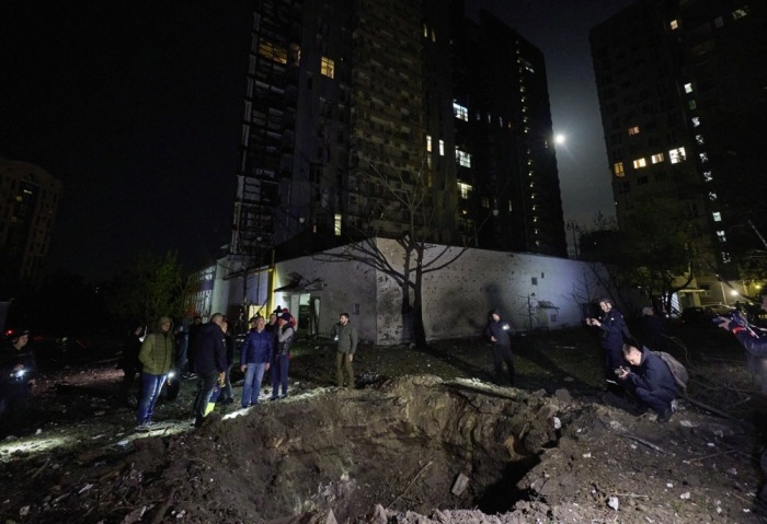 Leute stehen am Rande eines Granatenkraters zwischen Wohngebäuden nach einem Beschuss in Charkiw. Foto: epa/Sergey Kozlov
