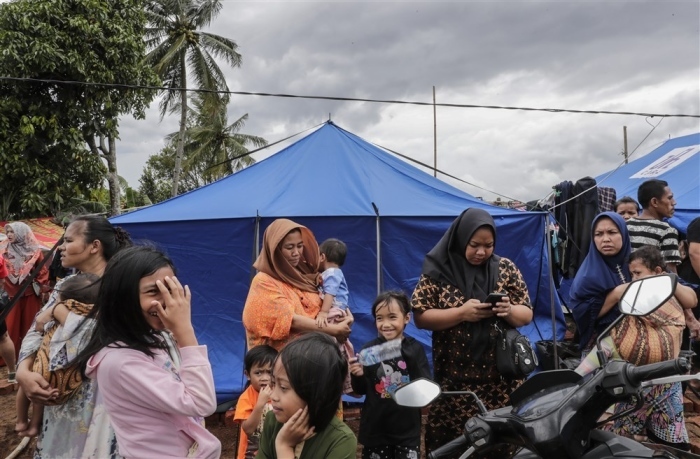 Menschen bleiben außerhalb ihrer Zelte, während starker Wind auf ein Feld bläst, das in einem Dorf, das von dem Erdbeben der Stärke 5,6 in Cianjur, Westjava, betroffen ist, zu einer Notunterkunft umfunktioniert wurde. Foto: epa/Mast Irham
