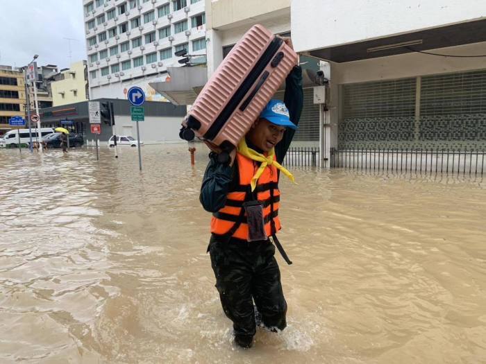 Ein Soldat trägt einen Koffer durch hüfttiefes Wasser während der Evakuierungen im überfluteten Stadtzentrum von Hat Yai. Foto: Royal Thai Army
