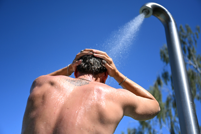 Ein Mann steht im Sommerbad Humboldthain unter der Dusche. Derzeit rollt eine Hitzewelle über Brandenburg und Berlin. Foto: Elisa Schu/dpa