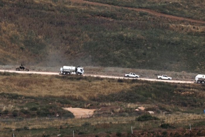 Ein israelisches Militärfahrzeug passiert nahe der Grenze zu Israel einen Konvoi der UN-Friedenstruppe UNIFIL im Südlibanon. Foto: epa/Atef Safadi