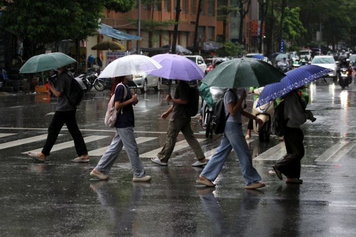 Menschen mit Regenschirmen gehen durch den Regen in Hanoi nach dem Eintreffen des Taifuns Bualoi. Mehrere Tote und Vermisste. Foto: epa/Luong Thai Linh