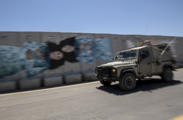 Ein israelisches Militärfahrzeug fährt an einem Graffiti an der Sicherheitsmauer vorbei, die in der Nähe des israelischen Moshavs Shtula an der israelisch-libanesischen Grenze errichtet wurde. Foto: epa/Atef Safadi