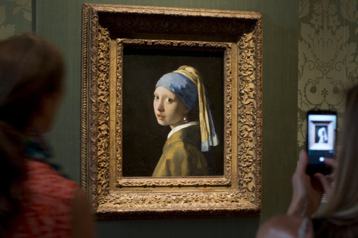 Besucher fotografieren das Gemälde «Das Mädchen mit dem Perlenohrgehänge» (1665-1667) des niederländischen Malers Johannes Vermeers während einer Vorbesichtigung für die Presse des renovierten Mauritshuis. Foto: Peter Dejong/Ap/dpa