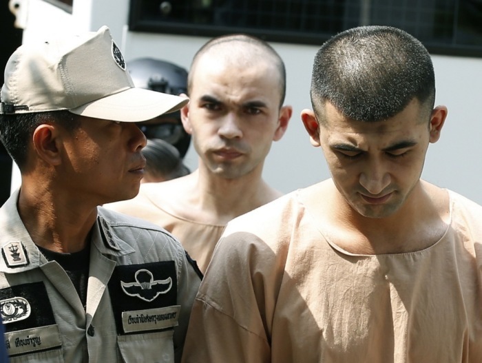 Die mutmaßlichen Erawan-Anschlagsverdächtigen Yusufu Mieraili (r.) und Adem Karadag (M.) werden von Polizisten und Justizvollzugsbeamten eskortiert. Foto: epa/Narong Sangnak