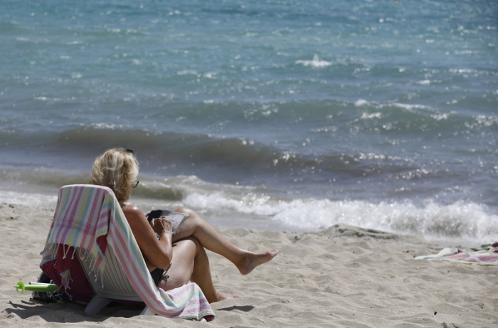 Eine Frau sonnt sich am Strand von Arenal. Auf Mallorca scheint es fast so, als hätte es nie einen Corona-Stillstand gegeben. Foto: Clara Margais/dpa