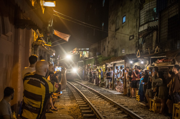 Die Touristen fotografieren einen Zug, der zwischen Häusern in einer Eisenbahnstraße im Alten Viertel in Hanoi fährt. Foto: epa/Roman Pilipey