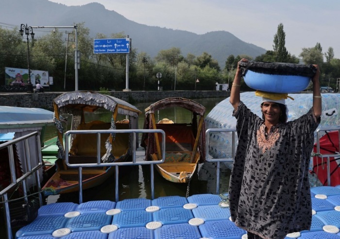 Eine Fischerin trägt einen Eimer mit frischem Fang am Dal-See in Srinagar und zeigt den Alltag der Menschen in Kaschmir. Foto: EPA/Farooq Khan