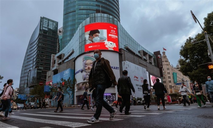 Leute überqueren die Straße neben einem großen Bildschirm, der für den Singles' Day in Shanghai wirbt. Archivfoto: epa/ALEX PLAVEVSKI
