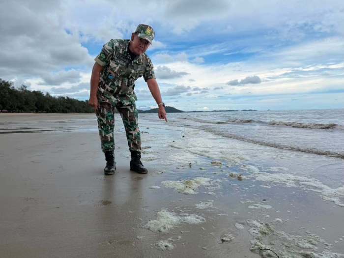 Ein Mitarbeiter des Nationalparks untersucht Schaumablagerungen am Mae Ramphueng Beach nach einer ungewöhnlichen Verfärbung des Meerwassers. Bild: Khao Laem Ya–Mu Ko Samet National Park