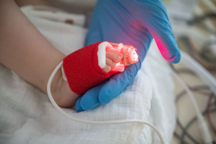 Eine Intensivpflegerin hält auf der Kinder-Intensivstation des Olgahospitals des Klinkums Stuttgart den Fuß eines am Respiratorischen Synzytial-Virus (RS-Virus oder RSV) erkrankten Patienten. Foto: Marijan Murat/dpa