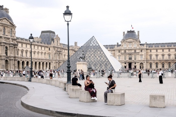 Besucher genießen einen Sommertag rund um das Louvre-Museum in Paris. Foto: EPA/Teresa Suarez