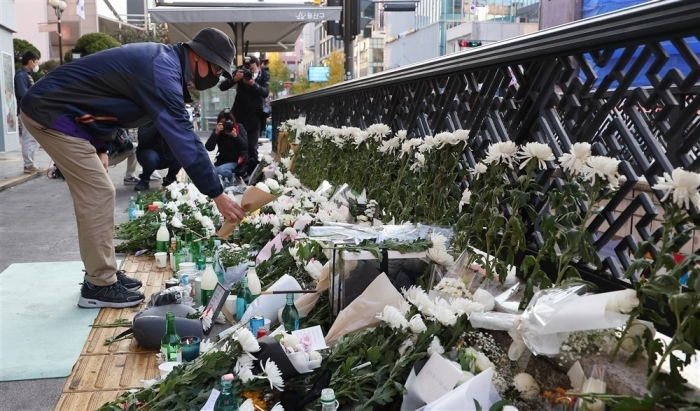 Eine Person legt Blumen auf einem provisorischen Trauerplatz in der Nähe des Schauplatzes einer tragischen Halloween-Stampede im Itaewon-Bezirk in Seoul nieder. Foto: epa/Yonhap