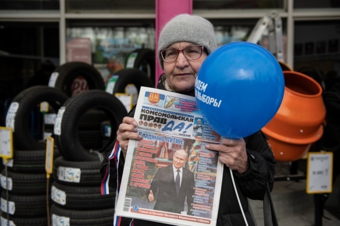 Die Frau hält eine Zeitung mit einem Foto des russischen Präsidenten Wladimir Putin. Foto: epa/Stringer