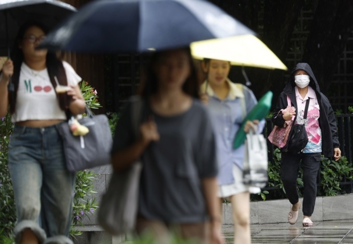 Passanten schützen sich in Bangkok mit Regenschirmen vor einem Regenschauer. Foto: epa/Narong Sangnak
