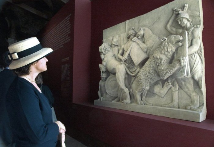 Eine Journalistin betrachtet ein antikes Relief mit der Darstellung von Gladiatorenkämpfen zwischen Gladiatoren und Raubkatzen in der Ausstellung «Sangue e Arena» (Blut und Arena) im Kolosseum. Foto: Del Castillo/Ansa/epa/dpa