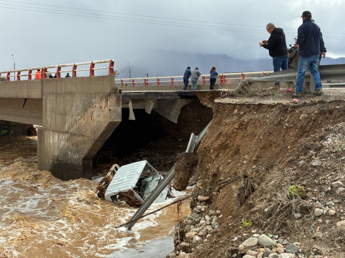 Ein Lastwagen befindet sich unter einer Brücke, nachdem er infolge eines Erdrutschs von der Maitencillo-Brücke in die Fluten gestürzt ist. Foto: Lucas Aguayo/Agencia Uno/dpa