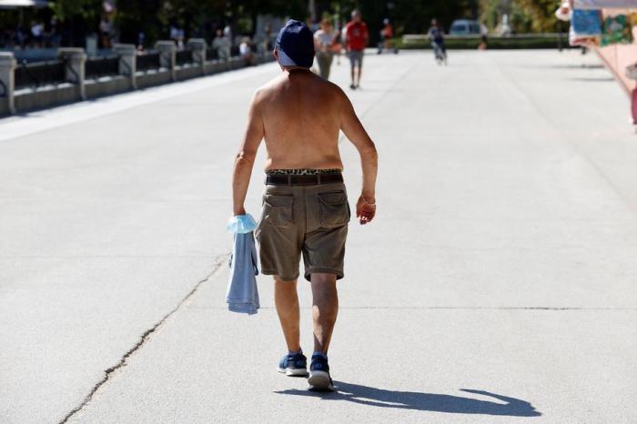 Ein Passant spaziert ohne Hemd durch den Retiro-Park in Madrid. Foto: epa/Chema Moya