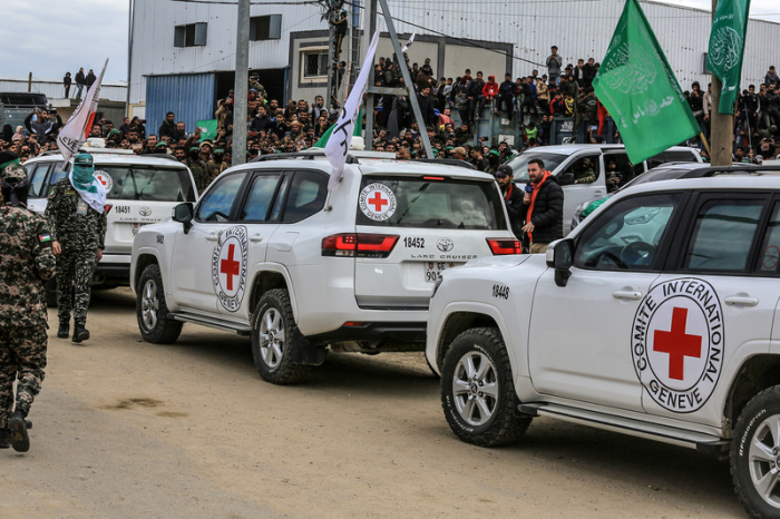 Fahrzeuge des Internationalen Roten Kreuzes stehen bereit, während Kämpfer der Hamas Geiseln an Vertreter des IKRK übergeben. Foto: Abed Rahim Khatib/dpa