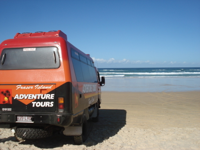 Ein Ausflugs-Truck mit dem Aufdruck Fraser Island steht am Strand. Foto: Carola Frentzen/dpa