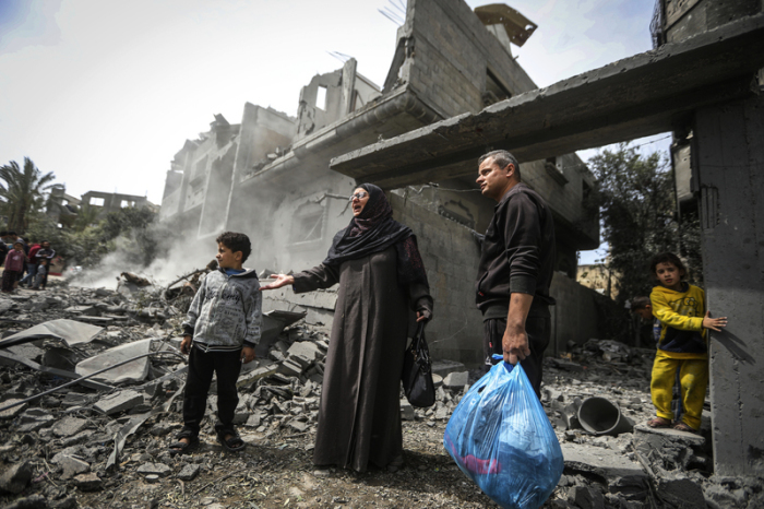 Palästinenser sammeln ihre Habseligkeiten aus den Trümmern eines Wohnhauses nach einem israelischen Luftangriff im Flüchtlingslager Maghazi. Foto: Ismael Abu Dayyah/Ap/dpa