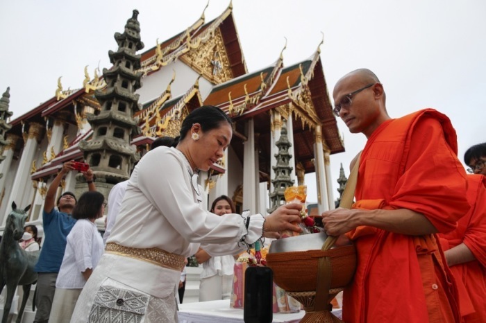Am frühen Morgen nehmen Buddhisten am Almosengang der Mönche Teil und werden gesegnet. Foto: epa/Rungroj Yongrit