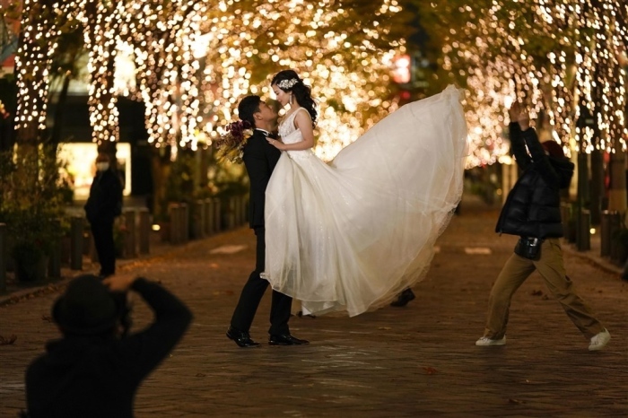 Ein Pärchen posiert für Fotos zur Erinnerung an seine Hochzeit mit saisonaler Beleuchtung in Tokio. Foto: epa/Kimimasa Mayama