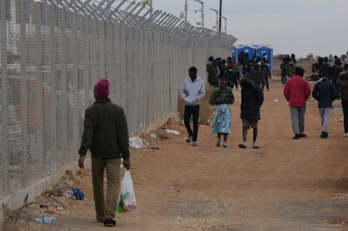 ersonen gehen an einem Zaun des Aufnahmezentrums für Migranten Pournara vorbei. Foto: Petros Karadjias/Ap/dpa