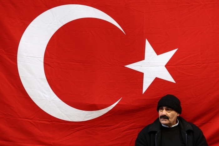 Alltag in Istanbul: Ein Mann sitzt nahe der Istiklal-Straße vor einer türkischen Flagge, während das Land politisch angespannt ist. Foto: EPA/Sedat Suna