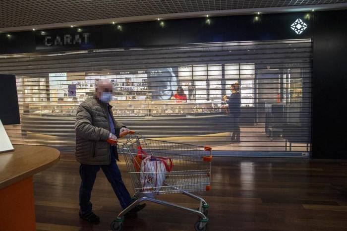 Ein mit einem Mundschutz maskierter Mann geht an einem geschlossenen Juweliergeschäft in einem Einkaufszentrum in Genf vorbei. Foto: epa/Salvatore Di Nolfi