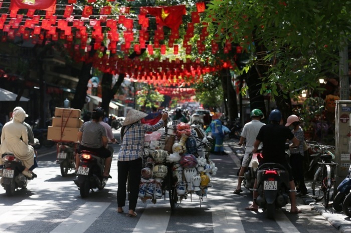 Eine Straßenhändlerin trägt Keramikwaren durch eine belebte Straße in Hanoi und bietet ihre Töpferarbeiten im Alltagsgeschäft zum Verkauf an. Foto: EPA/Luong Thai Linh