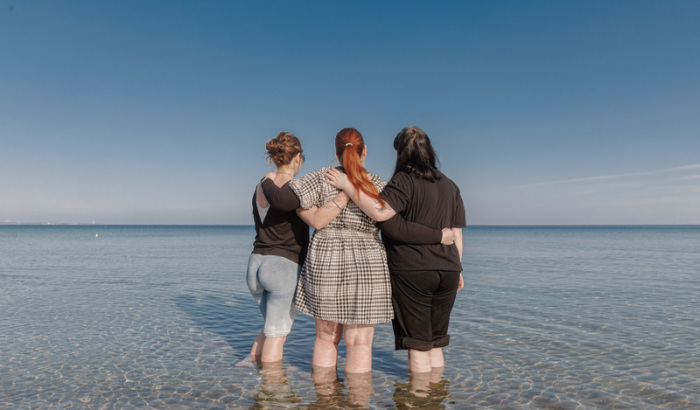 Drei Freundinnen genießen ein erstes Fußbad in der Ostsee – Sonne und milde Temperaturen locken an den Strand von Scharbeutz. Foto: dpa/Markus Scholz