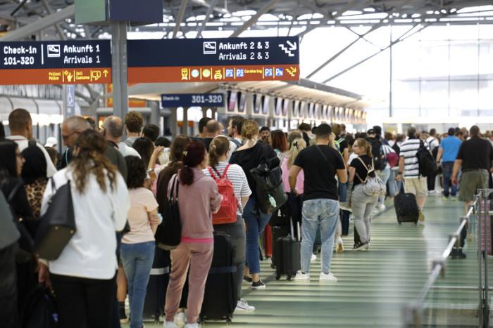 Passagiere stehen in einer Schlange von mehreren hundert Metern für die Sicherheitskontrolle am Flughafen Köln-Bonn an. Foto: Thomas Banneyer/dpa