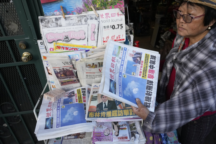 Die Geschäftsinhaberin Annie hält ein Exemplar der Zeitung «Chinese Daily News», auf dem Bilder eines mutmaßlichen chinesischen Spionageballons zu sehen sind. Foto: Damian Dovarganes/Ap/dpa