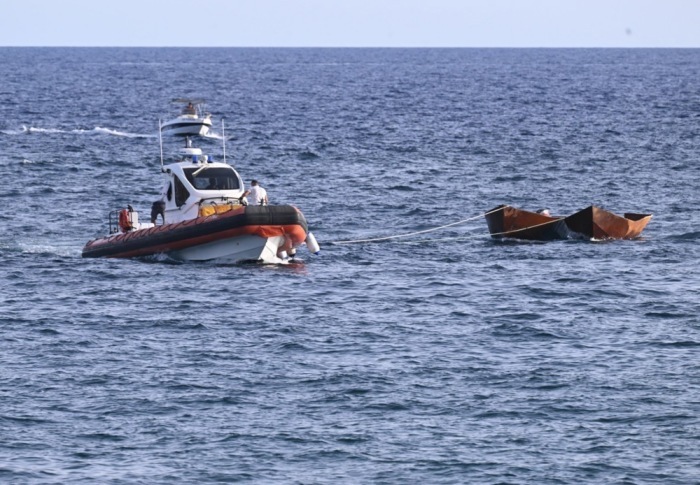 Mitglieder der Besatzung eines Bootes der italienischen Küstenwache ziehen zwei kleine Boote ab, in denen Migranten aus dem Meer gerettet wurden. Foto: epa/Ciro Fusco