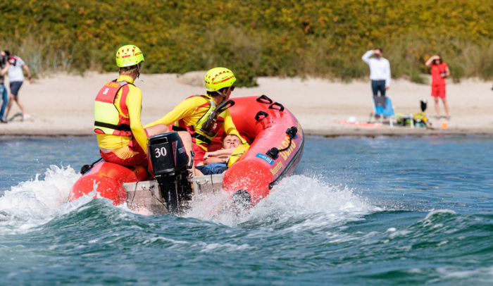 DLRG-Rettungsschwimmer bringen bei einer Übung einen Statisten zurück an den Strand. Foto: Markus Scholz/dpa