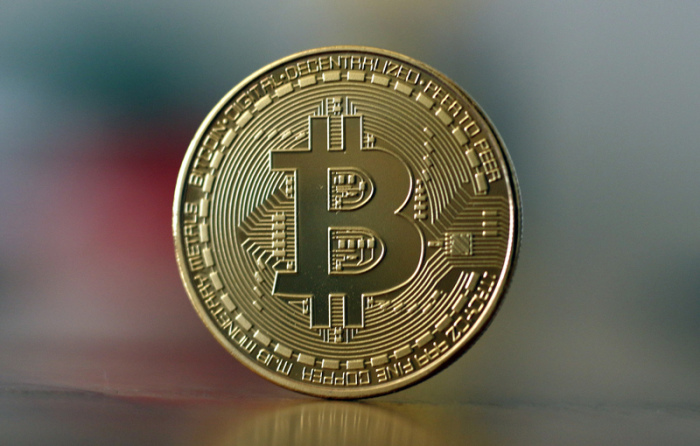 Eine Bitcoin Münze steht auf einem Tisch. Foto: Ina Fassbender/dpa