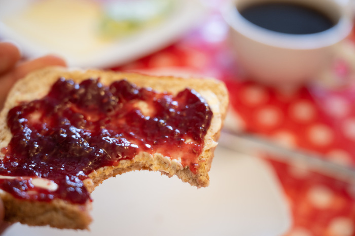 Ein Mann hält ein Toastbrot mit Himbeermarmelade in der Hand. Foto: Sebastian Gollnow/dpa