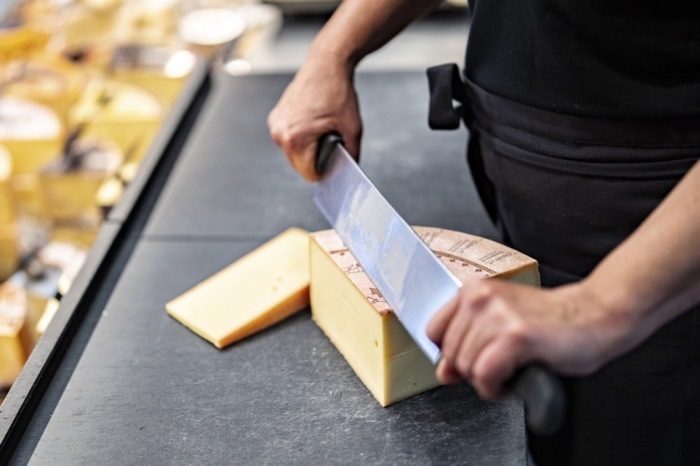 Eine Mitarbeiterin schneidet Käse Emmental. Neue US-Zölle belasten Exporte aus der Schweiz und weiter sorgen für Unsicherheit. Foto: epa/Til Buergy
