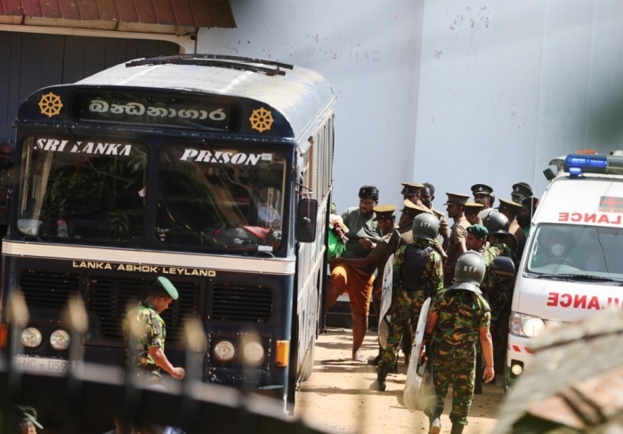 Sicherheitskräfte eskortieren Häftlinge nach den tödlichen Unruhen im Gefängnis von Negombo bei Colombo zu einem Bus. Foto: EPA/Stringer