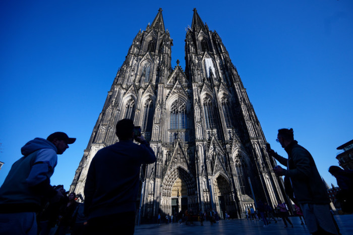 Touristen fotografieren den Kölner Dom. Künftig sollen Besucher für den Zugang zur berühmten Kathedrale Eintritt zahlen. Foto: dpa/Henning Kaiser