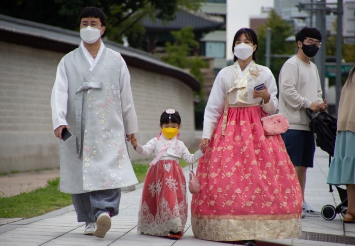 Ein Familie mit Gesichtsmasken und traditioneller Kleidung geht vor dem Gyeongbokgung-Palast in Seoul spazieren. Foto: epa/Jeon Heon-kyun