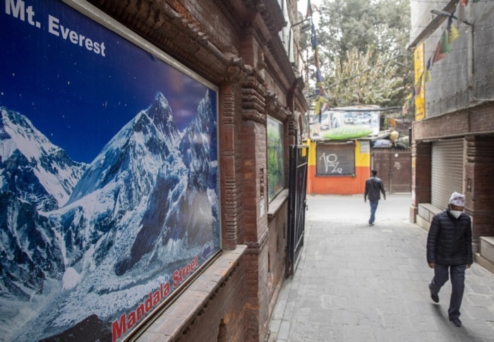Ein Mann mit einer Gesichtsmaske läuft vor dem Bild des Mount Everest in Thamel, einem wichtigen Touristenzentrum in Kathmandu. Foto epa/NARENDRA SHRESTHA