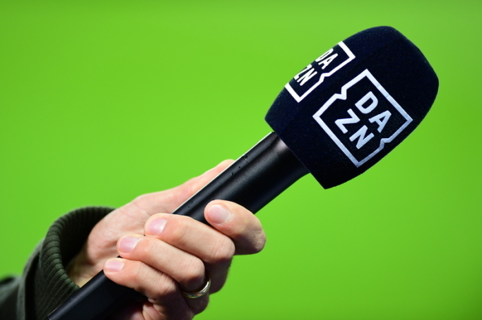 Die Hand eines Reporters hält bei einem Interview vor dem Spiel ein Mikrofon mit der Aufschrift DAZN. Foto: Soeren Stache/dpa-zentralbild/dpa