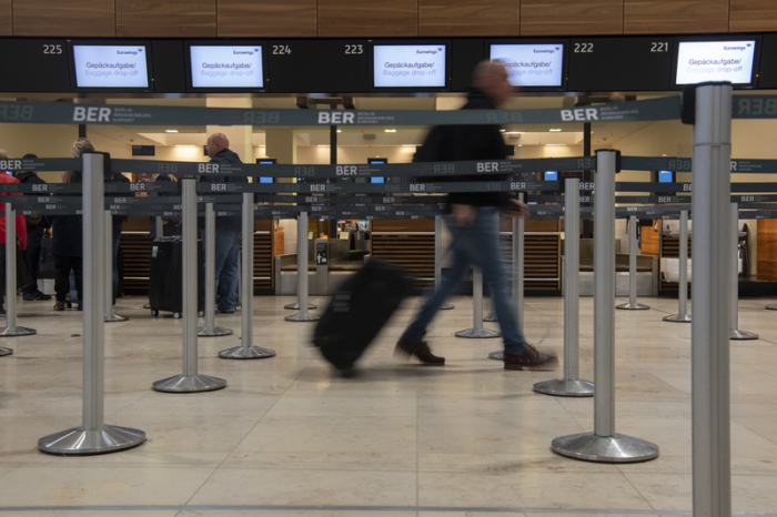 Ein Reisender geht mit einem Koffer zu einem Check-in-Schalter von Eurowings. Die Gewerkschaft Verdi hat für Mittwoch einen ganztägigen Warnstreik am Hauptstadtflughafen BER angekündigt. Foto: Paul Zinken/dpa