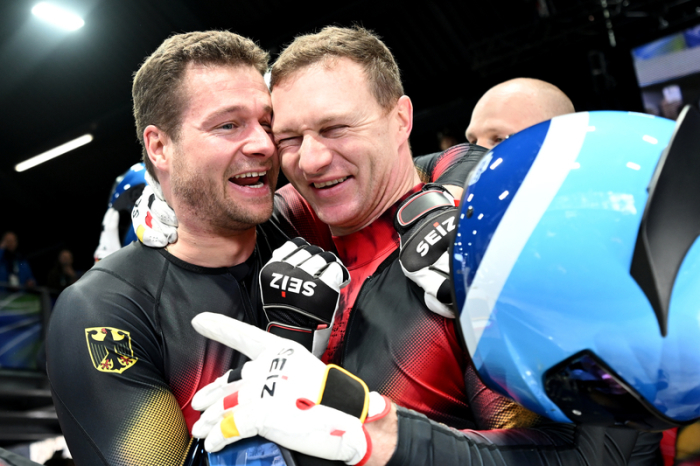 Johannes Lochner (l) und Francesco Friedrich feiern im Cortina Sliding Centre Gold und Silber im Viererbob bei Mailand-Cortina 2026. Foto: Robert Michael/dpa